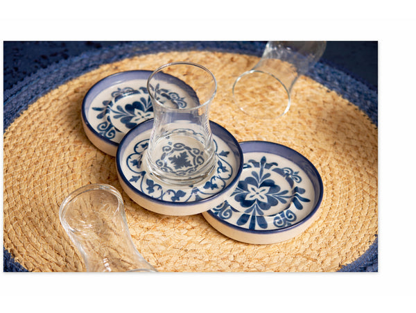 Set of blue and white ceramic coasters with matching glass on a woven placemat.